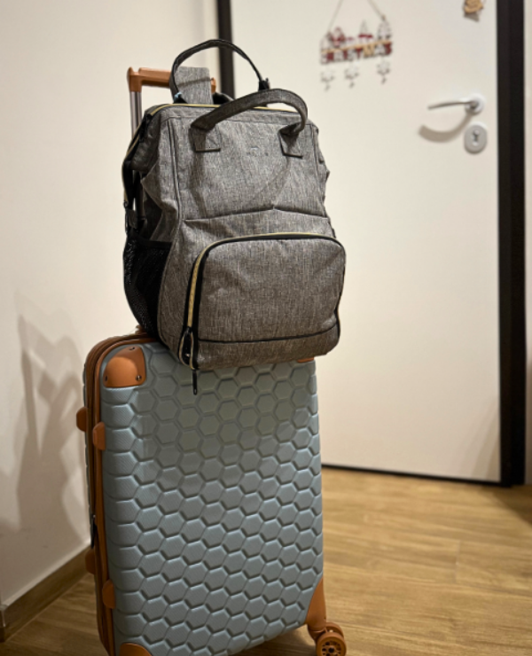 zaino borsa frigo grigio posato su valigia da viaggio, pronto per partire con un bambino